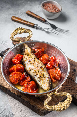 Fried halibut fish steaks with tomato in skillet. White background. Top viewの写真素材