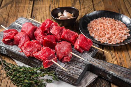 Raw beef shish kebab, Meat with spices and herbs on Skewers. Wooden background. Top viewの写真素材