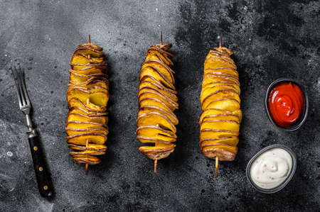 Roasted Tornado or twisted potatoes with ketchup sauce. Black background. Top view