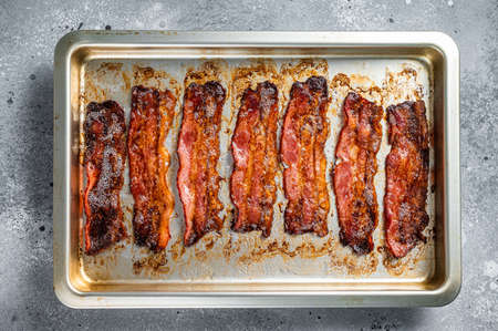 Strips of fried bacon in baking dish. Gray background. Top viewの写真素材
