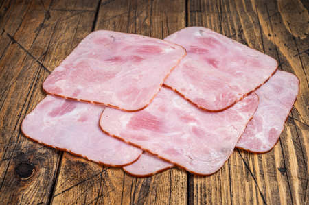 Square Slices of pork ham on wooden table. Wooden background. Top view