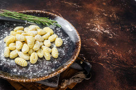 Italian gnocchi dumplings, Raw potato gnocchi on plate with thyme. Dark background. Top view. Copy spaceの写真素材