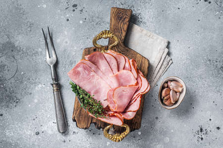 Slices of square sandwich ham with herbs in skillet. Gray background. Top view