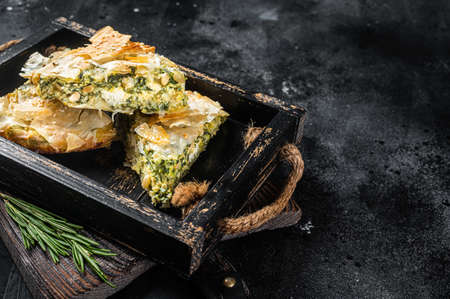 Spinach pie pieces, Spanakopita Greek Pie in wooden tray. Black background. Top view. Copy spaceの写真素材