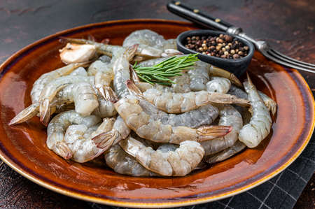 Black Raw uncooked Headless giant shrimps prawns in a rustic plate. Dark background. Top viewの写真素材