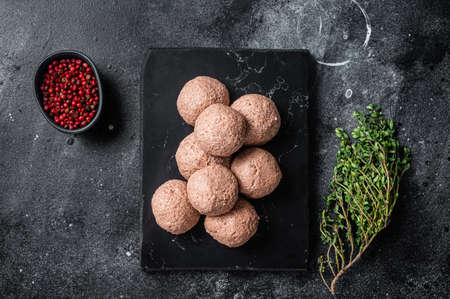 Raw vegan meatballs from plant based meat with thyme. Black background. Top view