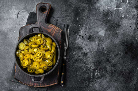 Pickled Green Sliced Jalapenos in a pan. Black background. Top view. Copy spaceの写真素材