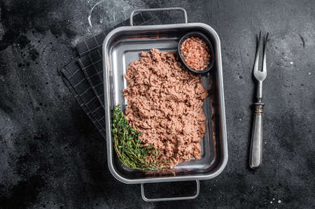 Vegetarian ground meat, raw plant based meat with herbs in kitchen tray. Black background. Top view