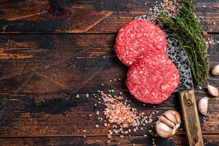 Raw steak cutlets with mince beef meat on a butcher cleaver. Wooden background. Top view. Copy spaceの写真素材