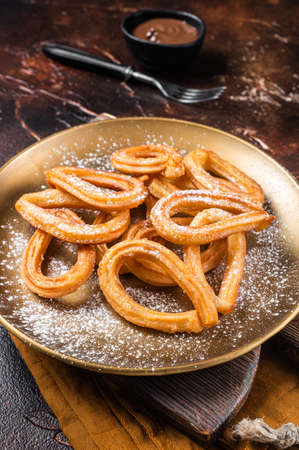 Spanish dessert churros with hot spicy chocolate. Dark background. Top view