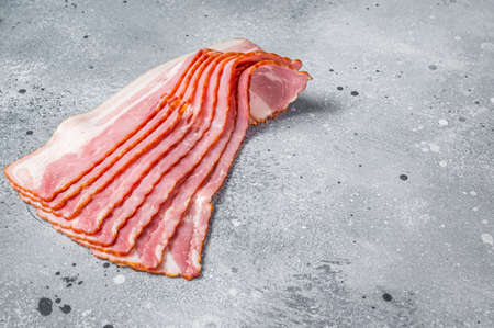 Raw bacon strips of pork meat. Gray background. Top view. Copy spaceの写真素材