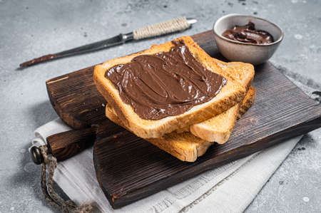 Toast with chocolate Hazelnut spread on wooden board. Gray background. Top view