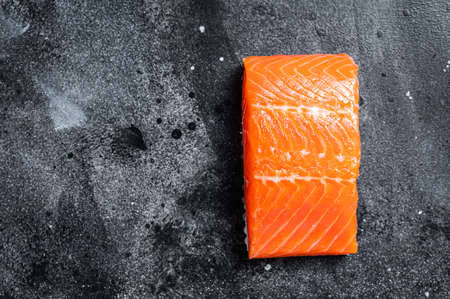 Raw salmon fillet steaks on kitchen table. Black background. Top view. Copy space