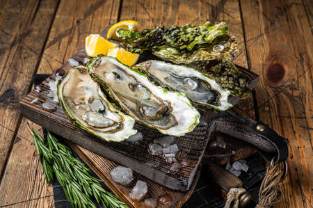 Oysters served on wooden board with ice and lemon. Wooden background. Top viewの写真素材