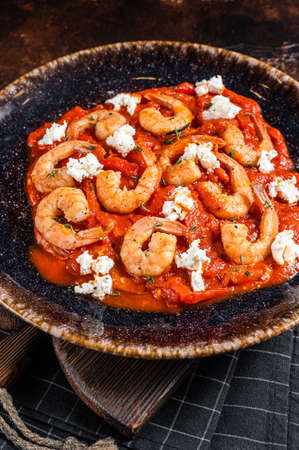 Saganaki Shrimp prawns with tomato and feta cheese on a plate. Dark background. Top view.の写真素材