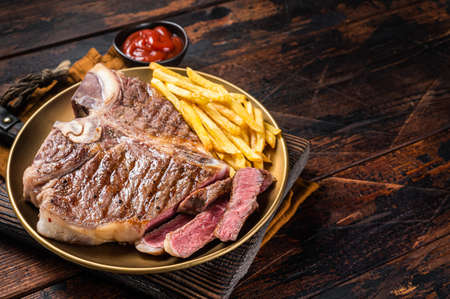 Roast Italian Florentine or porterhouse beef meat Steak in a plate with french fries. Wooden background. Top view. Copy spaceの写真素材