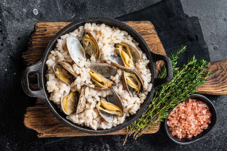 Seafood Risotto with clams in a skillet. Black backgroud. Top viewの写真素材