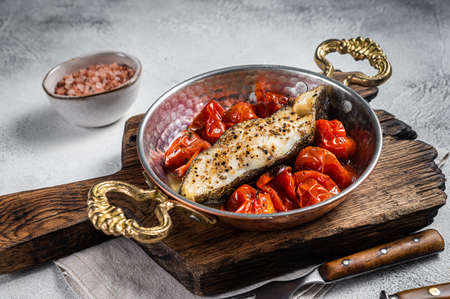 Fried halibut fish steaks with tomato in skillet. White background. Top viewの写真素材