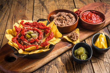 Traditional mexican refried beans with nachos, jalapeno and tomato sauce. Wooden background. Top view.の写真素材