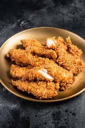Breaded chicken strips, breast fillet meat on a plate. Black backgrund. Top viewの写真素材