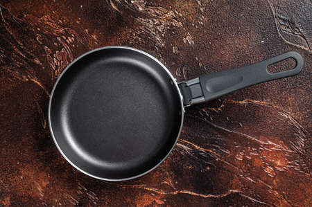 Empty iron frying pan on rustic table. Dark background. Top view. Copy space.の写真素材