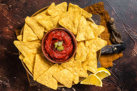 Nachos chips with tomato sauce and jalapeno, mexican appetizer. Dark background. Top viewの写真素材