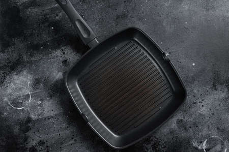 Empty cast-iron grill pan for cooking on rustic towel. Black background. Top view. Copy spaceの写真素材