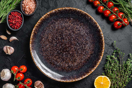Healthy eating vegan food concept background with empty plate and fresh seasoning, herbs and ingredients. Black background. Top view. Copy spaceの写真素材