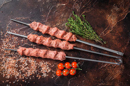Turkish adana kebab on Skewers from Raw mince lamb and beef meat, shish kebab. Wooden background. Top viewの写真素材