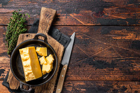 Parmesan hard cheese piece in a pan. Dark Wooden background. Top view. Copy spaceの写真素材