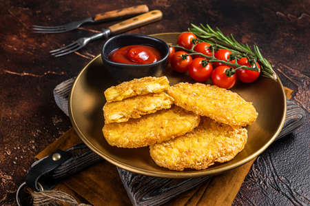 Roast Hash brown potato, Vegetable fritters in a plate with tomato sauce. Dark background. Top view
