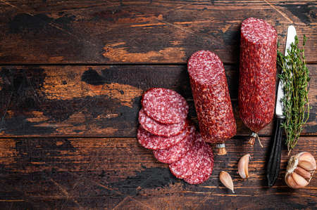 Sliced salami cured sausage on kitchen table. Wooden background. Top view. Copy space