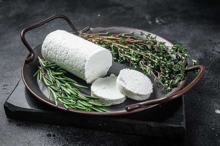 Chevre goat soft cheese with herbs on a tray. Black background. Top viewの写真素材