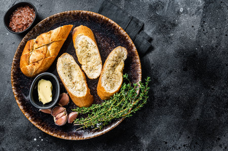 Garlic Spread on Toasted Baguette with Salt, Pepper, Thyme and Olive Oil in plate. Black background....