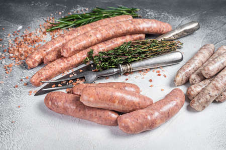 Raw Sausages variation - Beef, pork, lamb and chicken meat on a butcher table with rosemary and thyme. White background. Top viewの写真素材