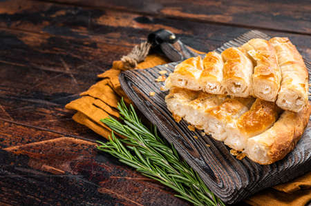 Homemade greek spanakopita pie with organic cheese on wooden board. Wooden background. Top view....