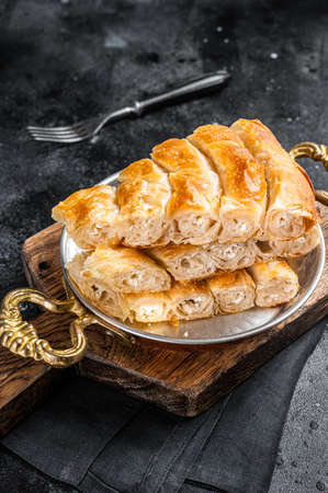 Traditional feta cheese phyllo pastry pie in rustic skillet. Black background. Top viewの写真素材