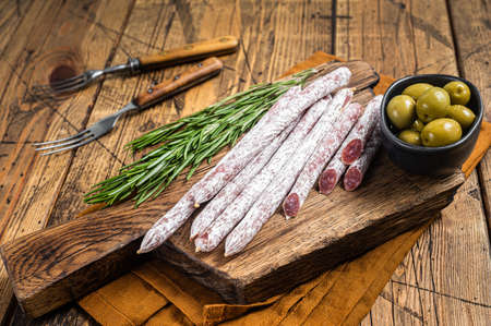 Spanish dry salami sausage Fuet with rosemary on wooden cutting board. Wooden background. Top viewの写真素材