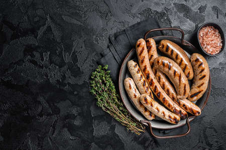 Grilled Bratwurst meat sausages on a steel tray with herbs. Black background. Top view. Copy spaceの写真素材