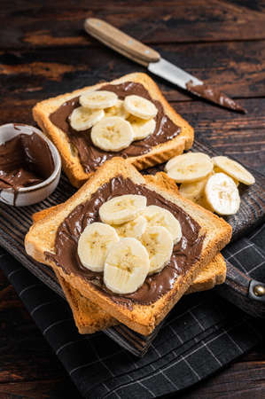 Toasts bread with bananas and chocolate cream on wooden board. wooden background. top view.の写真素材