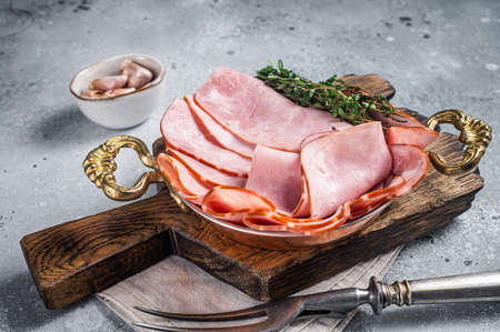 Slices of square sandwich ham with herbs in skillet. gray background. top view.