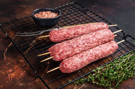 Raw Souvlaki Shashliks or Shish Kebab skewers with spices. dark background. top view.