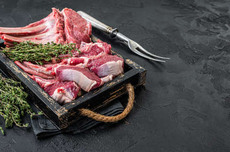 Uncooked Raw Rack and lamb, mutton rib chops in a wooden tray. Black background. top view....