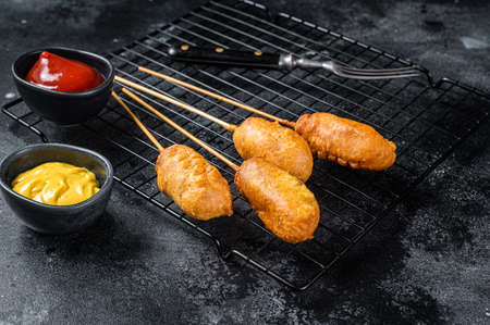 Deep fried corn dogs with mustard and ketchup. Black background. top view.の写真素材
