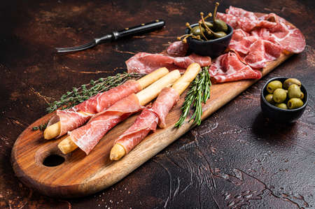 Meat appetizer platter with grissini sticks, Prosciutto crudo, Salami and Coppa Sausage and olives. dark background. top view.の写真素材