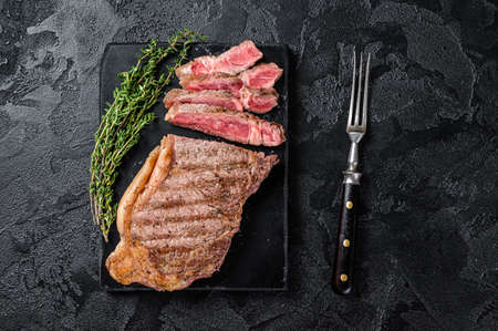 Griiled on BBQ sliced Striploin marbled beef meat steak. Black background. top view.の写真素材