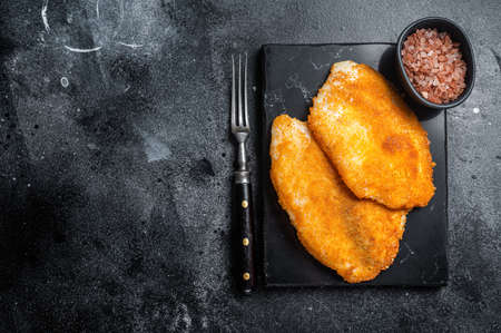 Fried breaded tilapia fillets on a marble board. Black background. top view. copyspace.