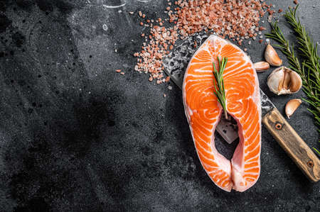 Raw Salmon trout Fish Steak on butcher table with meat cleaver. Black background. top view. copyspace.の写真素材