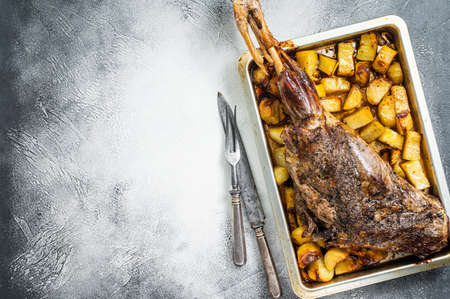 Roast lamb mutton leg with potatoes and rosemary in baking dish. white background. top view. copyspace.の写真素材