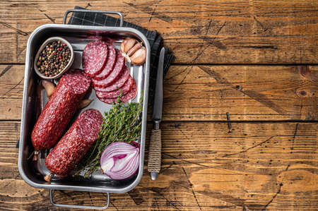 Italian Sliced Dry salami sausage in steel tray. wooden background. top view. copyspace.の写真素材